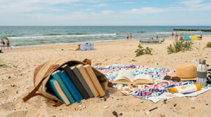 Obraz przedstawia sielankowy, wakacyjny widok na piaszczystą plażę w słoneczny dzień